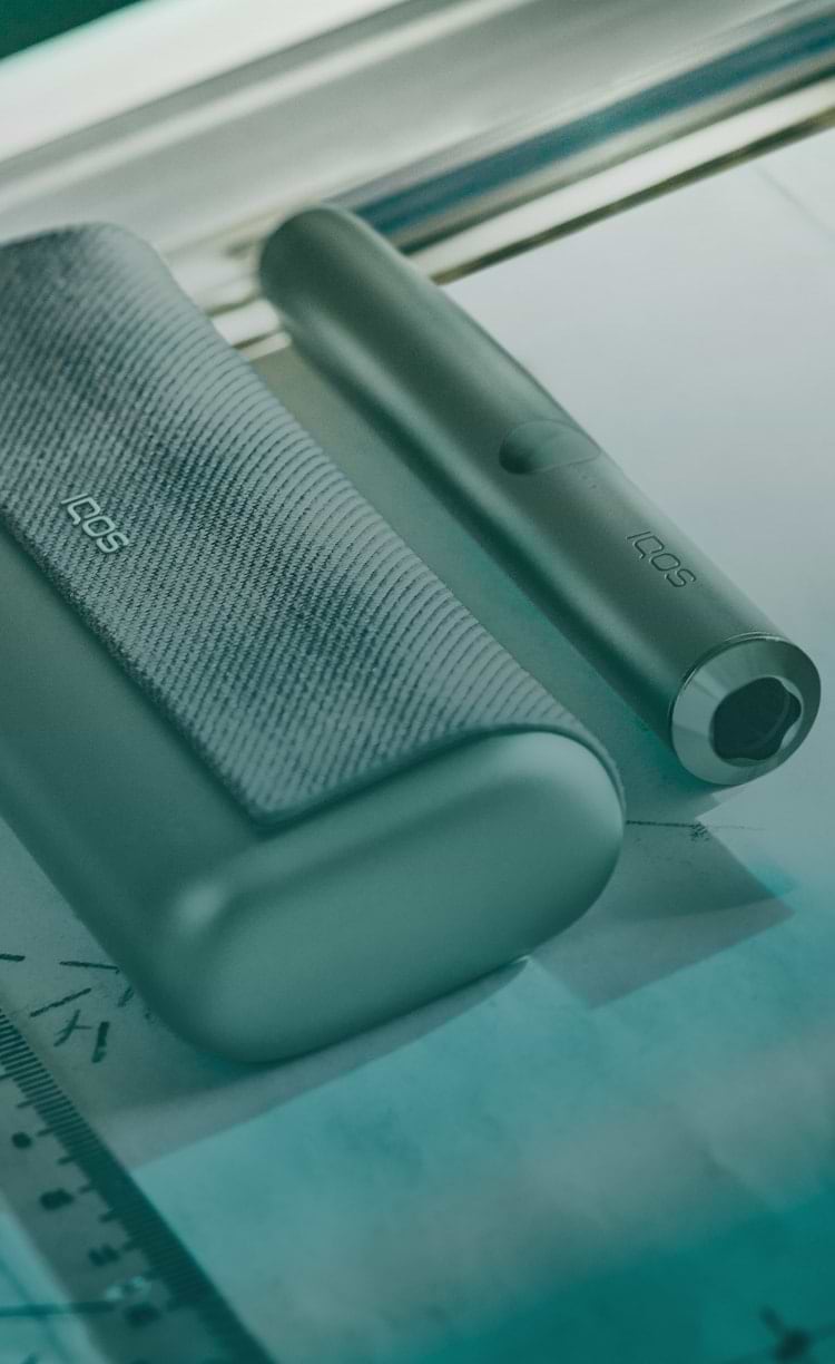 An IQOS ILUMA Pocket Charger and Holder on a laptop.