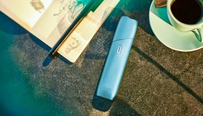 Turquoise IQOS Originals ONE heated tobacco device on a table.	 	 	