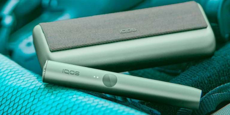 A person holding an unopened IQOS device box.