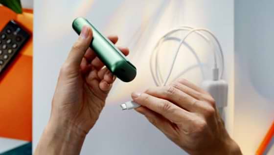 A charging cable being inserted into an IQOS ILUMA PRIME holder.
