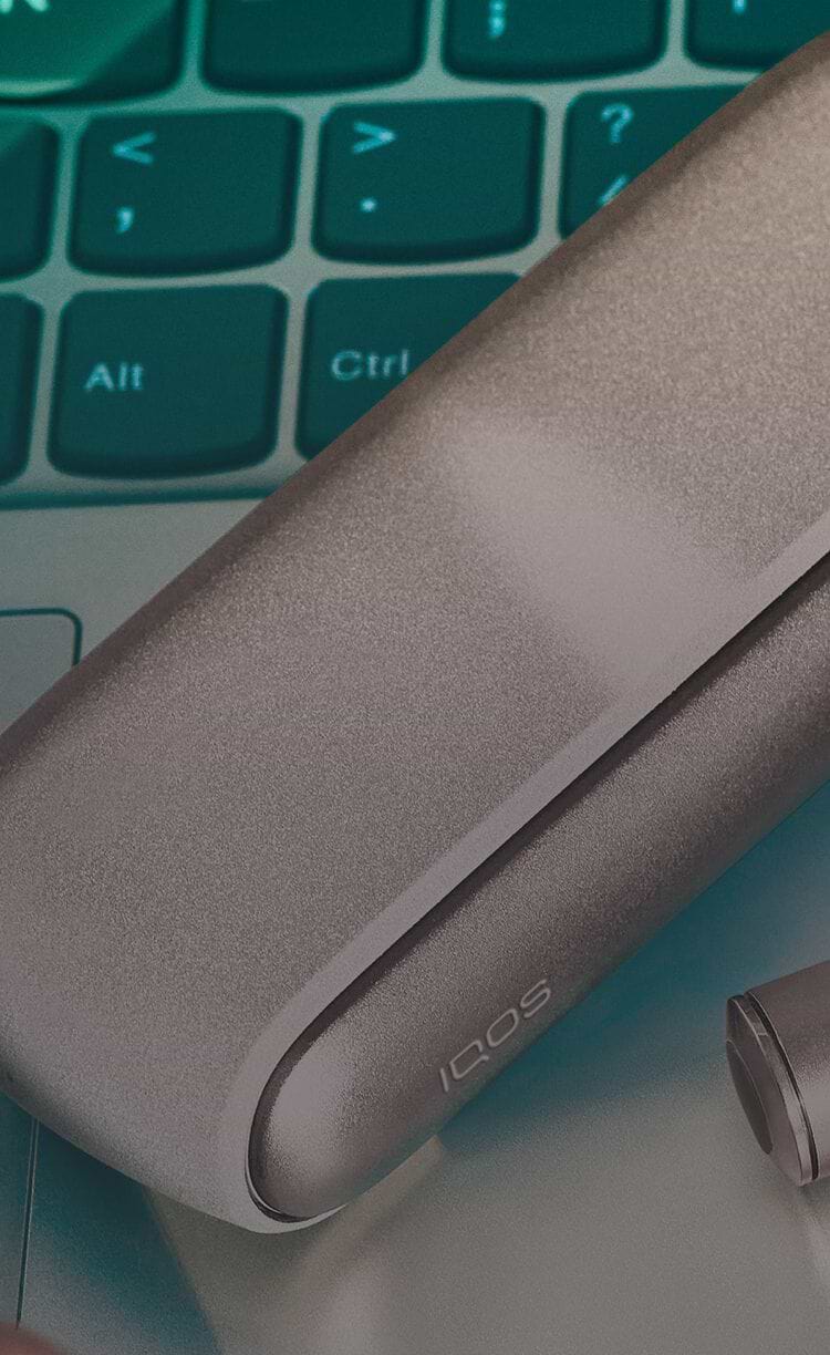 An IQOS ILUMA Pocket Charger and Holder on a laptop.