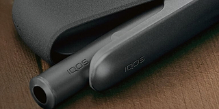 A person holding an unopened IQOS device box.
