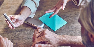 Hands holding smartphones and one IQOS device.