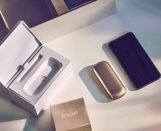 Turquoise IQOS Originals One device on a wooden table.