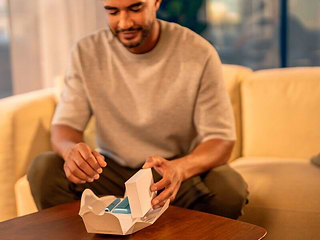 A person holding an unopened IQOS device box.