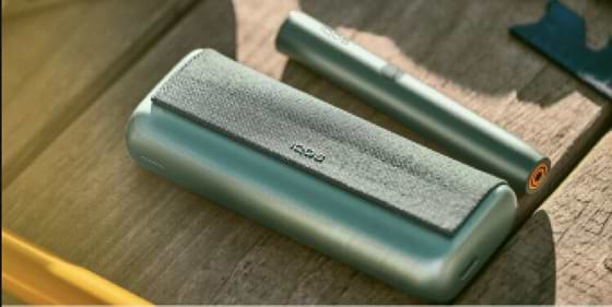 A person placing an IQOS ILUMA Pocket Charger into a charging station.