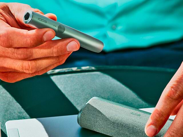 Green IQOS ILUMA PRIME Pocket Charger on a table.