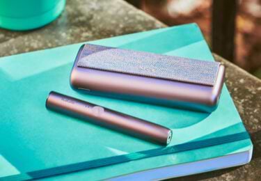  A mid azure blue IQOS ILUMA product sits on an architect's desk.