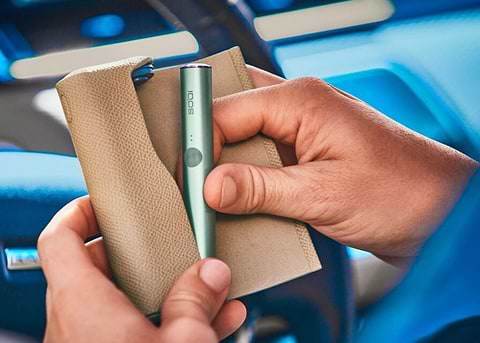 Close up of a hand holding a jade green IQOS ILUMA device.