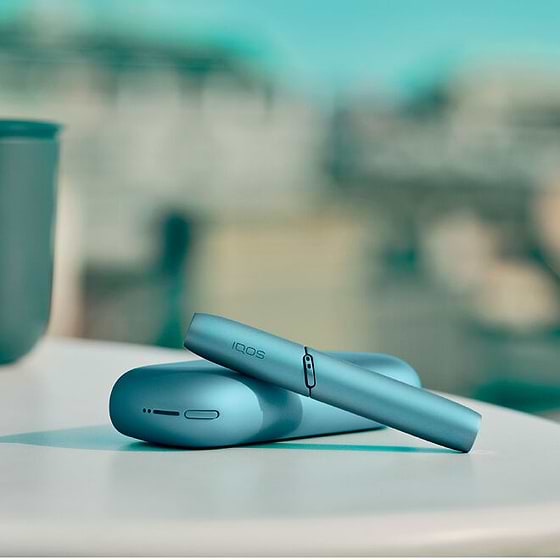 Turquoise IQOS Originals Duo holder and pocket charger on table.	 	 	