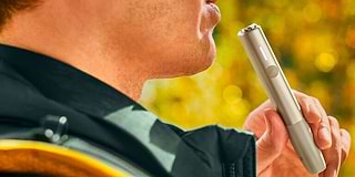 Two people holding phones over two cups of coffee.