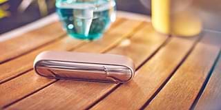 Man on a couch with his IQOS kit and the mobile in his hands