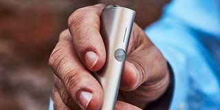 Hands holding smartphones and one IQOS device.