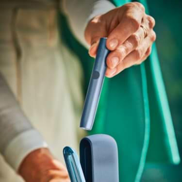 An architect takes a mid azure blue ILUMA device from its charger.