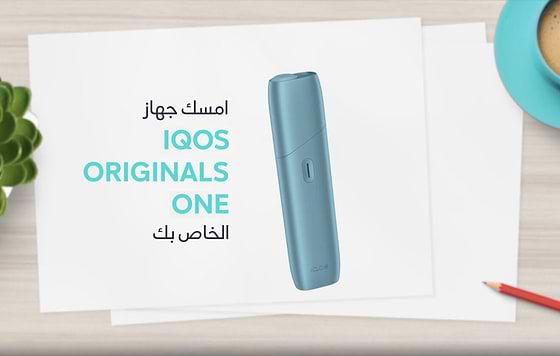 IQOS ORIGINALS ONE heated tobacco device in turquoise next to cable charger.	 	 	