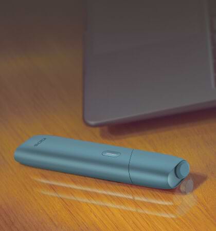 Turquoise IQOS Originals One device on a wooden table.	 	 	