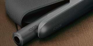 A person holding an unopened IQOS device box.