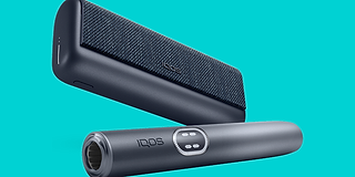 A woman sitting at a table next to her suitcase with a smartphone, passport and plane ticket.