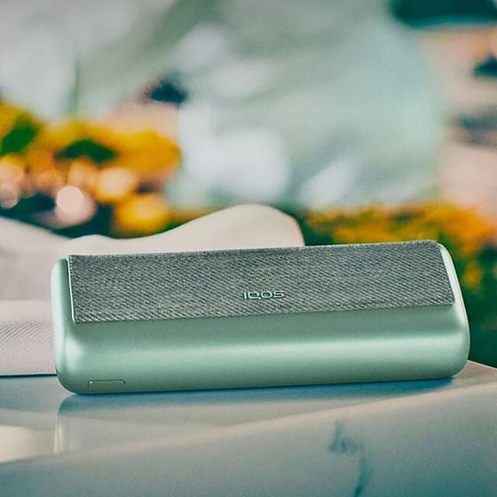Green IQOS ILUMA PRIME Pocket Charger on a table.