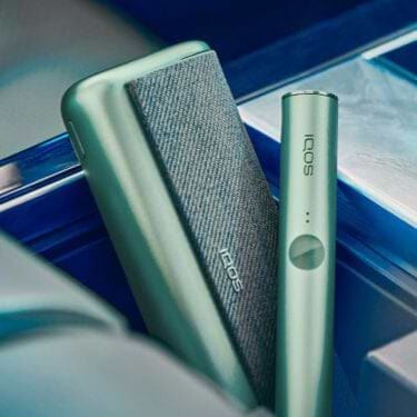 A jade green IQOS ILUMA device and holder.