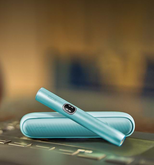 An IQOS ILUMA Pocket Charger and Holder on a laptop.