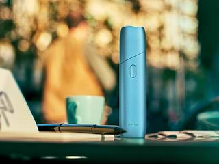 Turquoise IQOS Originals One device on a coffee table.	 	 	
