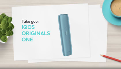 IQOS ORIGINALS ONE heated tobacco device in turquoise next to cable charger.	