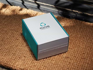 Woman opening an IQOS box delivered to her home	 	 	