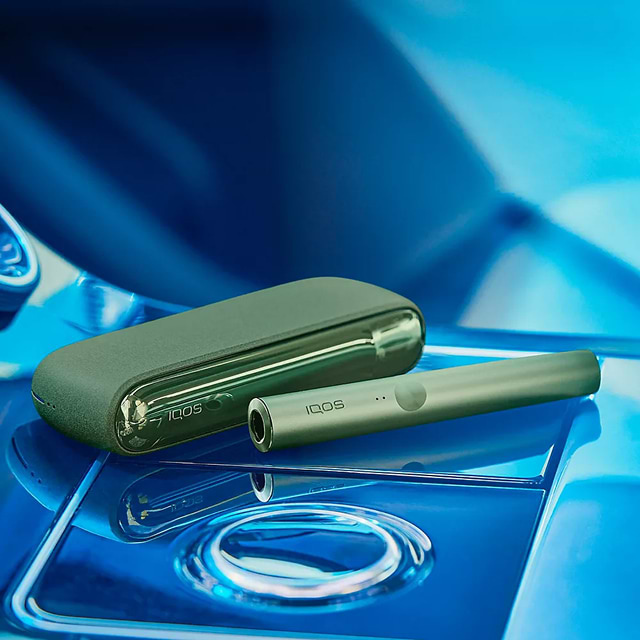 A woman looking at the back of an IQOS box.