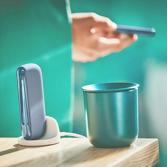 An IQOS device on a desk next to papers.