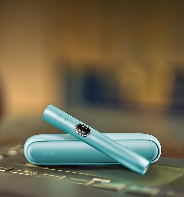 An IQOS ILUMA Pocket Charger and Holder on a laptop.